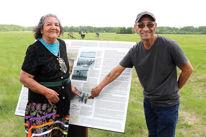 Siblings Rod Boyer and Marjorie Boyer pointing at themselves in a family photo at the original location on Beaver Creek at Fort Ellice in 1959, on a plaque at one of stations at the Fort Ellice site.<br />
